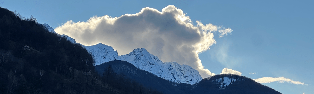cloud above snowy mountain lit by hiding sun