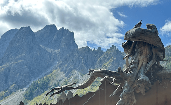 View of the Dolomites behind one of the carve-wood station of the Lost Spirits Trail.